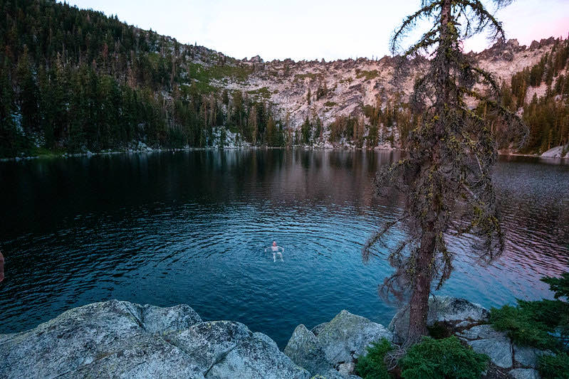 A still alpine lake ringed by rock and pines