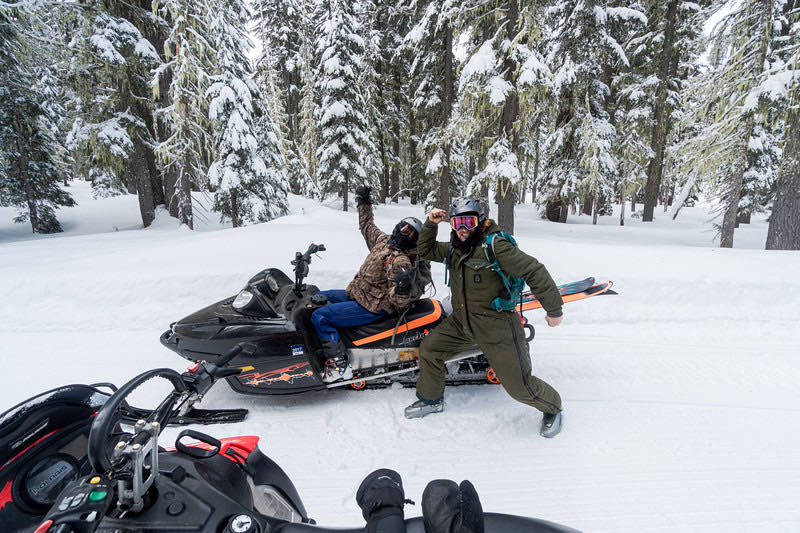 Two riders celebrating on a snowmobile
